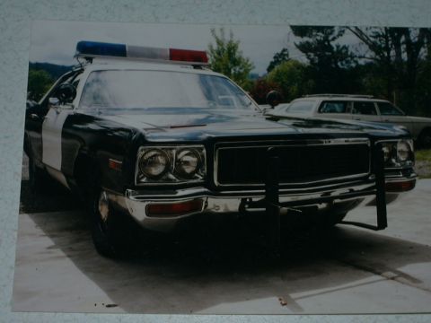 1991 Ford Crown Victoria - 1975 Dodge Monaco police car, not a 1991 Ford Crown Victoria. Another vehicle is visible in the background.