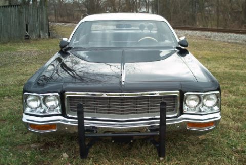 1991 Ford LTD Crown Victoria - Front view of a dark vintage full-size sedan with dual round headlights, chrome grille, and a black tubular push bumper.