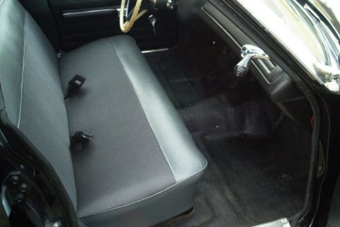 1991 Ford LTD Crown Victoria - Rear bench seat of a vintage car upholstered in dark gray vinyl, with chrome door trim and rubber floor mat visible.