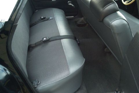 1991 Ford LTD Crown Victoria - Rear bench seat upholstered in two-tone gray and black vinyl with seat belts, viewed through an open door of a dark-colored car.