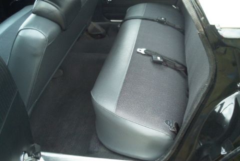 1991 Ford LTD Crown Victoria - Rear bench seat covered in gray and black vinyl with a seat belt buckle, seen inside a dark car interior.