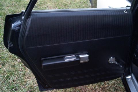 1991 Ford LTD Crown Victoria - Black vinyl interior door panel with chrome door handle and round lock knob, door opened above a grassy surface.