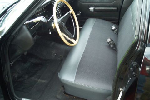 1991 Ford LTD Crown Victoria - Front gray and black bench seat with a light tan-rimmed steering wheel and dark dashboard, viewed through the open driver door.