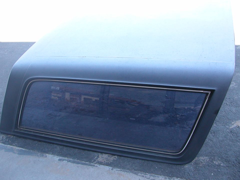 Gray primered removable SUV hardtop with tinted side window sitting on asphalt