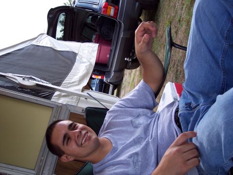 2001 Ford Crown Victoria - Man relaxing outdoors next to a pop-up camper and an SUV with its tailgate open.
