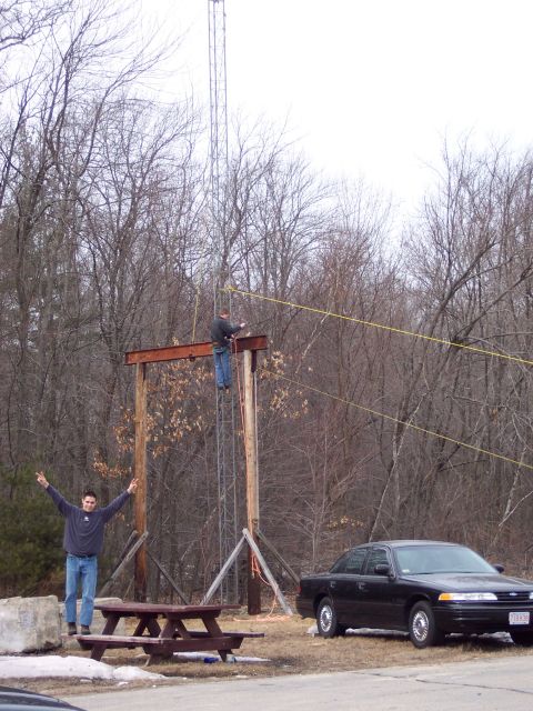 2001 Ford Crown Victoria - A black 2001 Ford Crown Victoria is parked near a picnic table while two men work on a tower in the background.