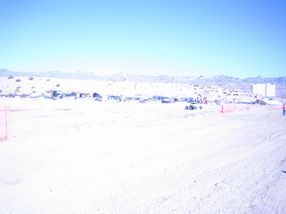 Wide view of a desert off-road racing pit area with parked vehicles