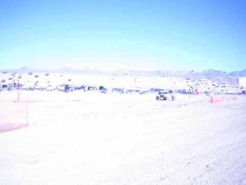 1990 Ford Bronco - bright wide shot of a sandy desert race course with a small off-road buggy near the distant pit area.
