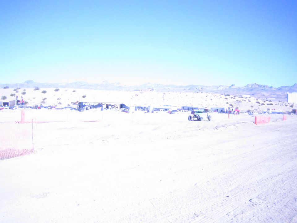 Wide view of a desert off-road race course with a buggy near the pits