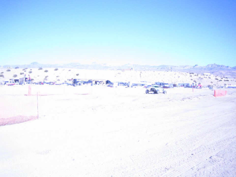 Off-road buggy on a sandy desert course with pits behind