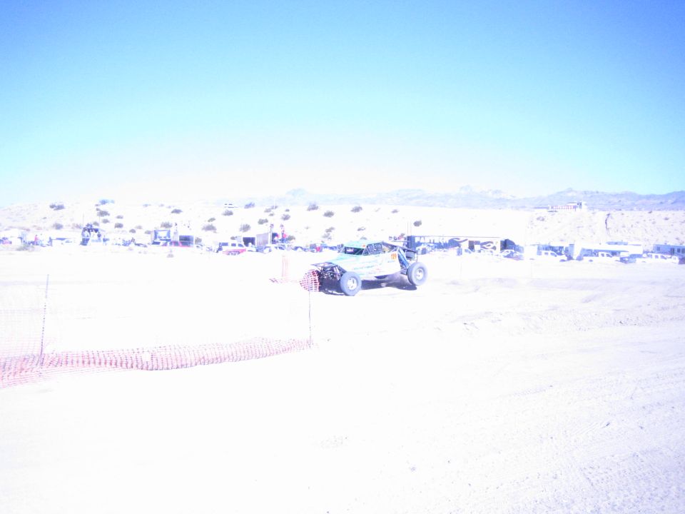 Off-road buggy on a sandy desert course behind orange fencing