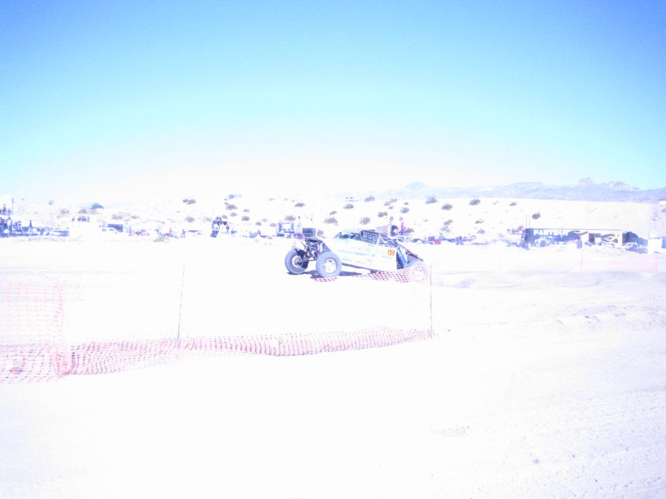 Off-road race buggy on a sandy desert course with numbered panel