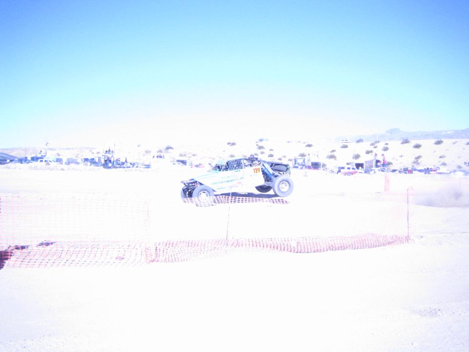 White off-road buggy kicking up dust on a sandy desert course
