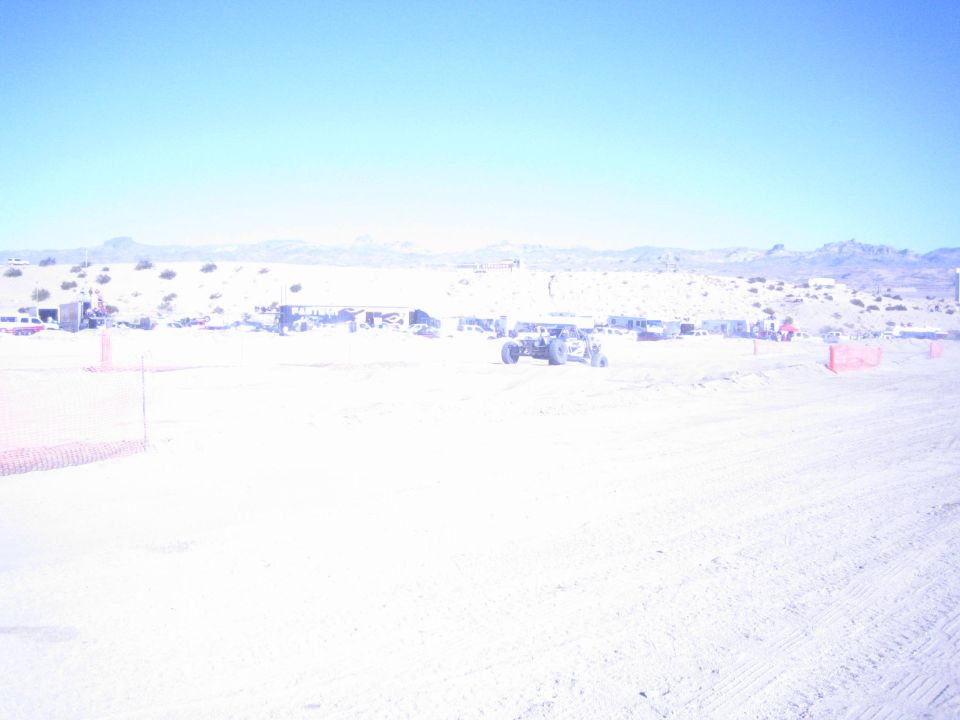 Single off-road buggy on a wide desert race course below low mountains