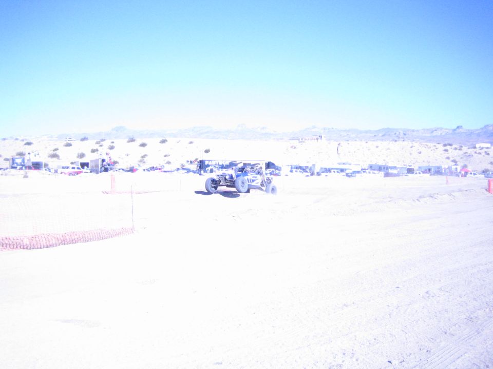 Tube-chassis off-road buggy on a desert race course under a deep blue sky
