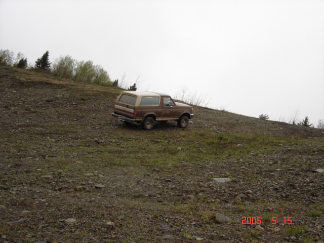 1990 Ford Bronco parked on a gravelly slope with sparse vegetation