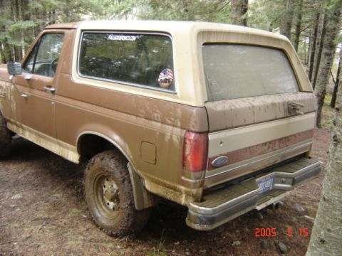 1990 Ford Bronco - This muddy 1990 Ford Bronco is seen in a wooded area, likely after off-roading.