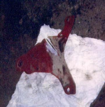 1989 Ford Bronco - A red metal bracket with white paint marks is shown on a white paper surface.