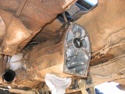 1986 Ford F-150 - Transmission housing removed for repair, revealing internal workings and heavily rusted chassis components.