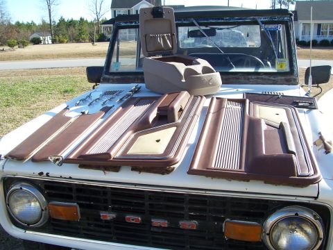 1978 Ford Bronco - Interior trim pieces are laid out on the hood of a classic Ford Bronco.
