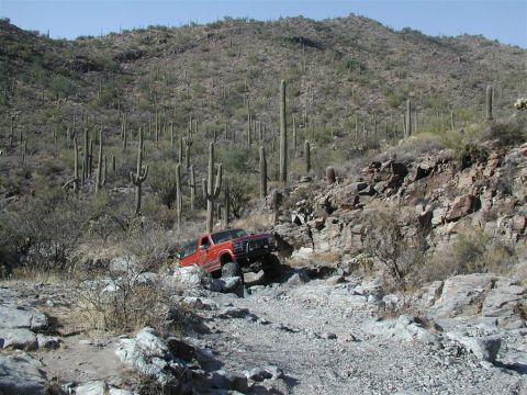 1994 Ford Bronco - 1994 Ford Bronco tackling a challenging rocky path in a desert landscape.