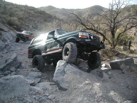 1994 Ford Bronco - Two SUVs, including a 1994 Ford Bronco, tackle a challenging rocky off-road course.