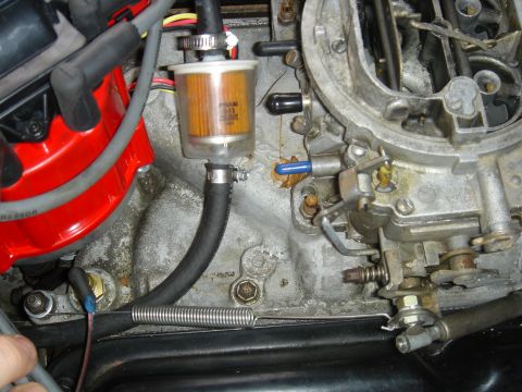 1986 Ford Mustang - Close-up view of an engine's carburetor and fuel filter assembly.