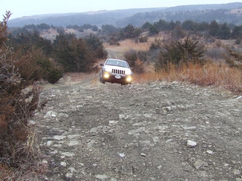 1994 Ford Bronco - Jeep Grand Cherokee navigates a rough, unpaved road through a natural landscape.