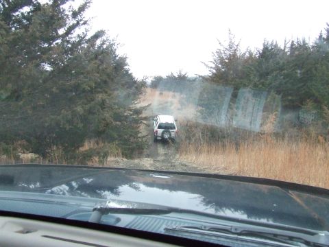 1994 Ford Bronco - Two vehicles on a dirt road surrounded by trees and dry grass.