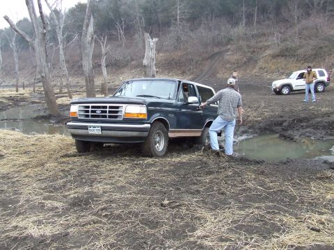 1994 Ford Bronco - Ford Bronco navigating muddy off-road conditions, with a second SUV visible in the background.