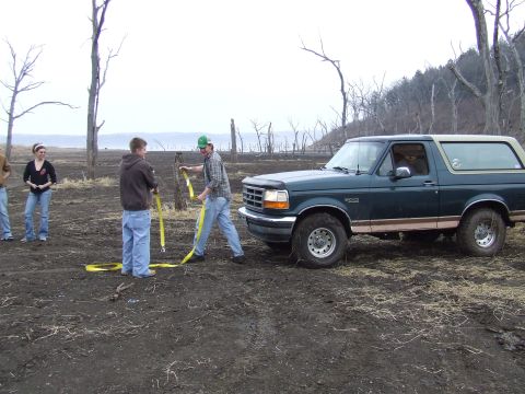 1994 Ford Bronco - Four people are gathered around a dark green 1994 Ford Bronco in a muddy, outdoor setting.
