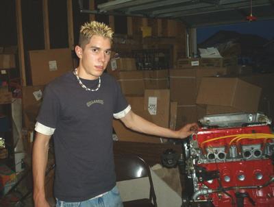 1994 Mazda MX-3 - Person standing next to a red engine block with yellow spark plug wires in a garage.