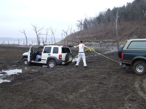 1994 Ford Bronco - A Jeep Liberty is stuck in thick mud while a Ford Bronco attempts to tow it out.