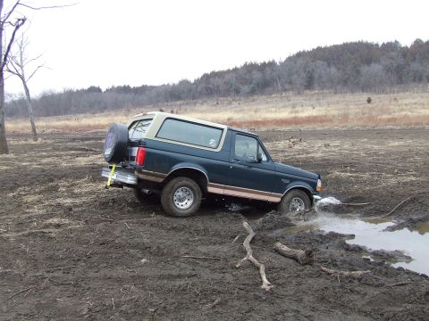 1994 Ford Bronco - This 1994 Ford Bronco is stuck in a muddy field, with its rear spare tire mounted and visible.