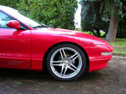 1996 Ford Probe - A red 1996 Ford Probe GT is shown from the front quarter angle, aftermarket rims and a GT badge on the door.