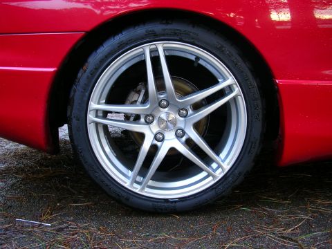 1996 Ford Probe - A close-up shot focuses on the wheel and tire assembly of a red vehicle.