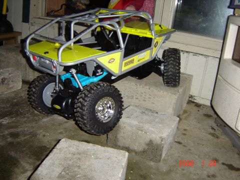 1993 Ford Bronco - This remote control rock crawler features a yellow body and silver roll cage, positioned on concrete blocks.