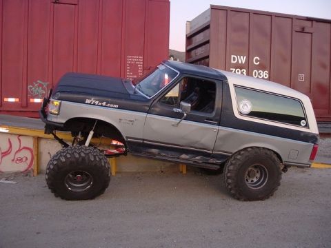 1989 Ford Bronco - This modified 1989 Ford Bronco features a two-tone paint scheme and oversized tires, parked beside freight train cars.