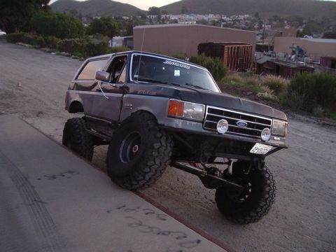 1989 Ford Bronco - This modified Ford Bronco is shown on an incline with its front right wheel significantly elevated.