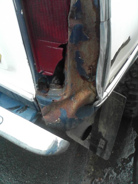 1978 Ford Bronco - The rear corner of the vehicle shows significant rust and damage, with the taillight broken and metal peeling away.