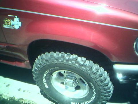 1996 Ford Explorer - Close-up of a red SUV's fender and off-road tire, a decal on the fender.