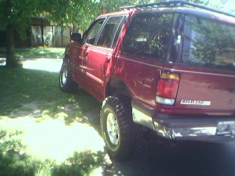 1996 Ford Explorer - Red 1996 Ford Explorer parked on a lawn with trees in the background.