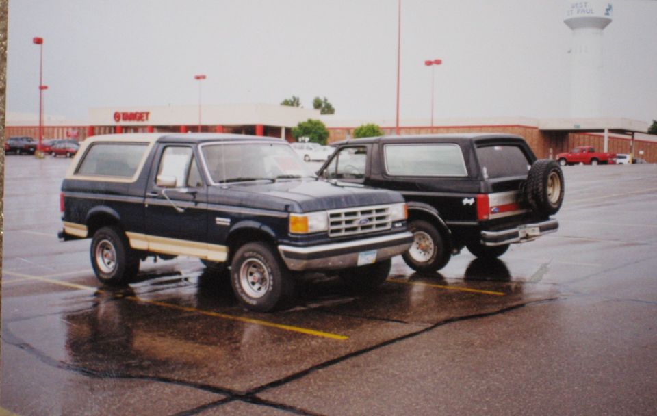 Two dark blue Ford Broncos parked facing each other in a rainy Target parking lot