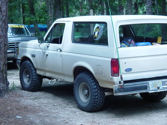 White 1989 Ford Bronco rear 3/4 view with off-road tires and a license plate reading '168 TIE'