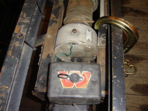 1992 Ford Bronco - Close-up of a winch mechanism and trailer frame, with a C-clamp securing a metal component.