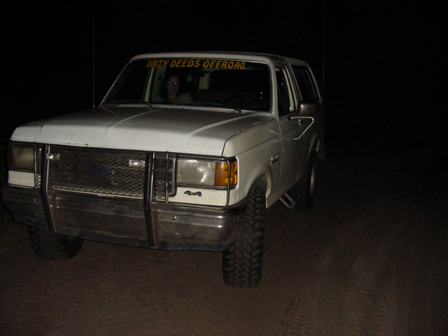 White 1989 Ford Bronco with brush guard and "DIRTY DEEDS OFFROAD" sticker on windshield