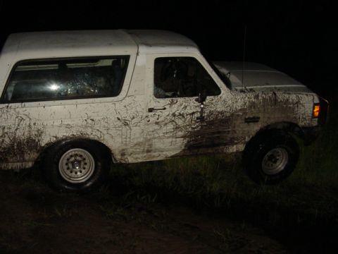 1989 Ford Bronco - This muddy SUV appears to be stuck in the dirt after an off-road excursion.