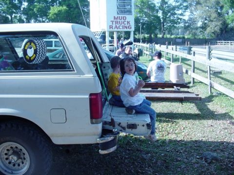 1989 Ford Bronco - Children sit on the tailgate of a 1989 Ford Bronco at a mud truck racing event.