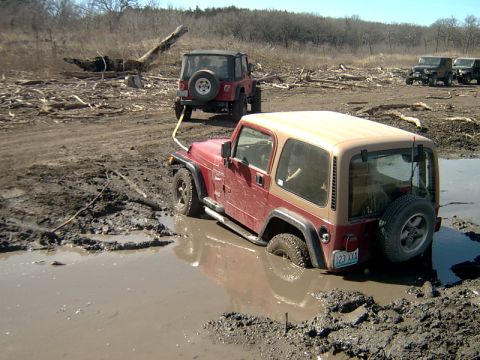 1998 Jeep TJ - This 1997 Jeep TJ is stuck in the mud, being pulled by another Jeep while others watch.