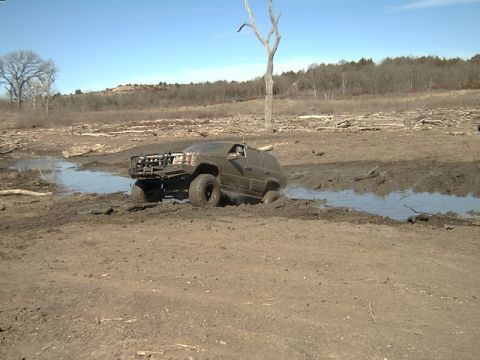 1998 Jeep TJ - A Jeep Grand Cherokee navigates a muddy terrain with a prominent grille guard.